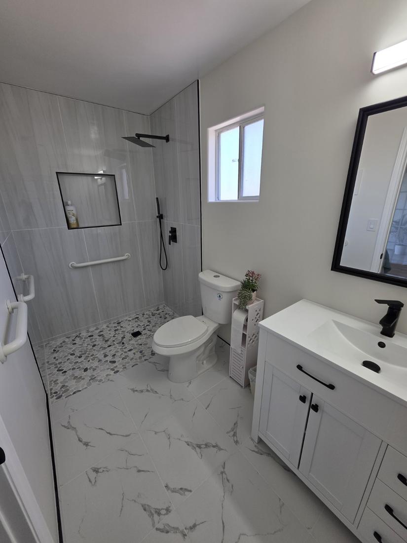 Modern bathroom with curbless tiled shower, pebble floor and grab bar