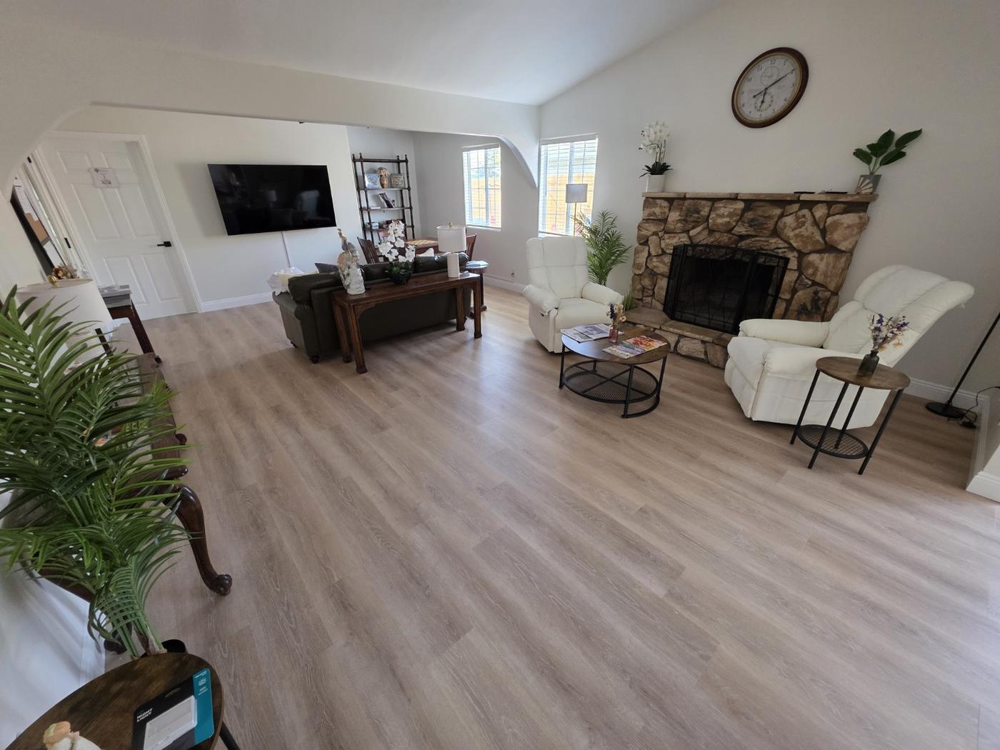 Open living room with vaulted ceiling, sofa, recliners and a stone fireplace