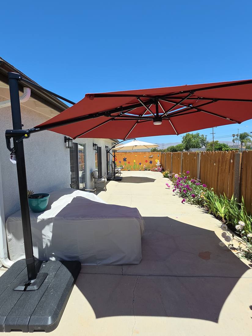 Backyard patio with cantilever umbrellas, flower beds and a painted garden fence